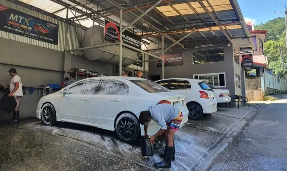 Crew member washing a white Honda Civic at Wholesome Concepts