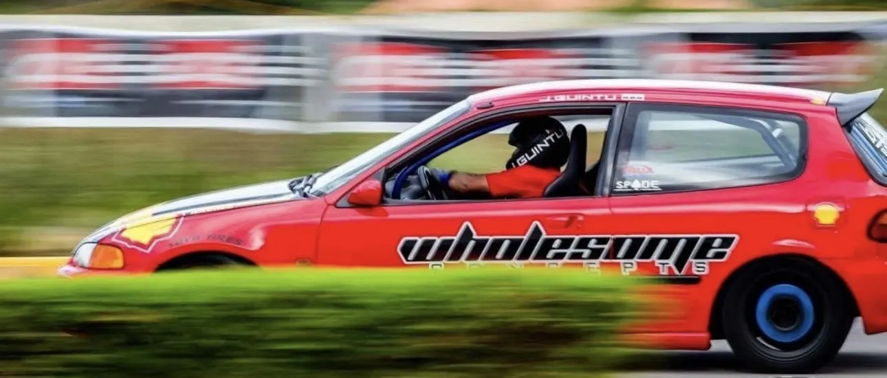 The red Wholesome Concepts Civic in a panning shot at an autocross event