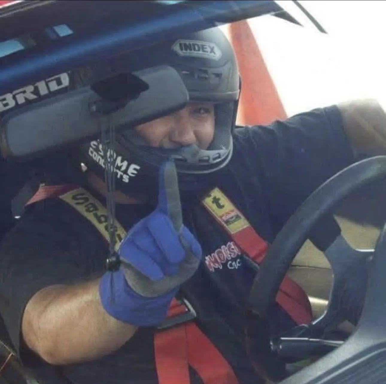 Jonathan Guintu in helmet and harness, giving a number one sign from the driver's seat